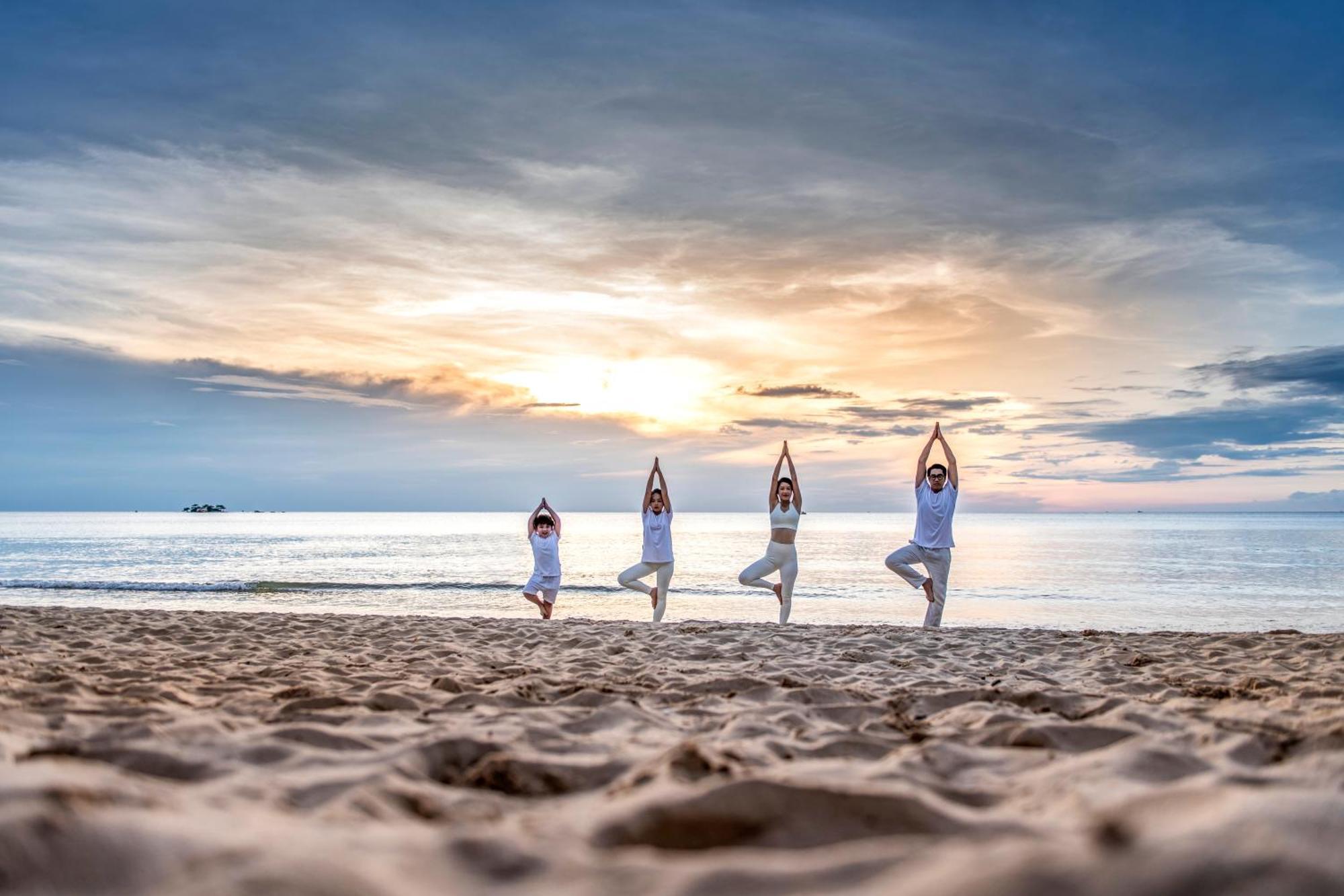 Vinpearl Resort & Spa Phu Quoc Exterior foto Family practicing yoga on the beach